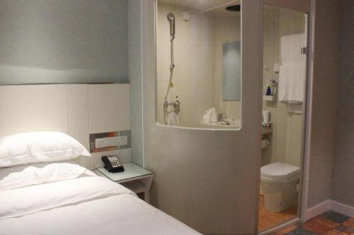 a bedroom with a bed and a bathroom with a toilet at Zaozhuang Hotel in Zaozhuang