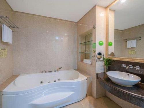 a bathroom with a large white tub and a sink at Chinflux Mandarin Hotel in Dongguan