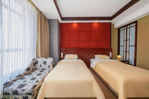 a bedroom with two beds and a red wall at Chinflux Mandarin Hotel in Dongguan