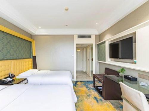 a hotel room with two beds and a flat screen tv at Zaozhuang Hotel in Zaozhuang