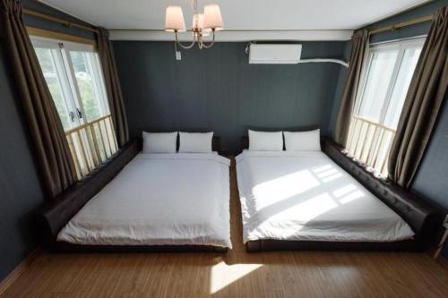two beds in a room with two windows at All That Water Pension in Gapyeong