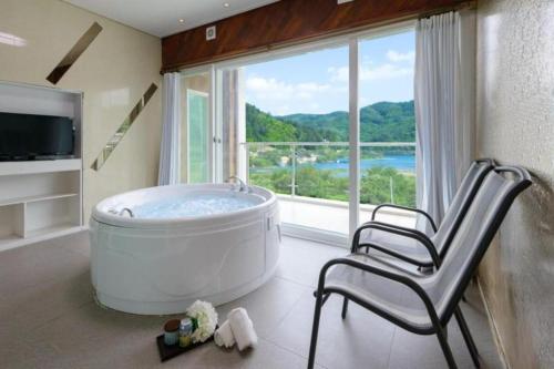 a large bathroom with a tub and a chair in front of a window at All That Water Pension in Gapyeong