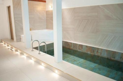 a swimming pool with a tub in a room with lights at All That Water Pension in Gapyeong