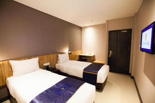 a hotel room with two beds and a flat screen tv at Fitra Hotel Majalengka in Majalengka