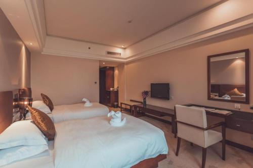 a hotel room with two beds and a desk at Kunming Wenhui Hotel in Kunming