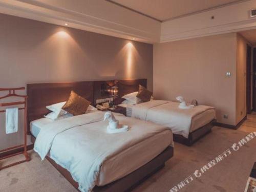 a hotel room with two beds with white birds on them at Kunming Wenhui Hotel in Kunming