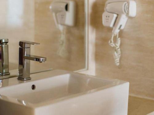 a sink in a bathroom with a phone on the wall at Oriental Hotel in Dongguan