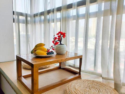 a table with a bowl of fruit and a vase of flowers at Oriental Hotel in Dongguan