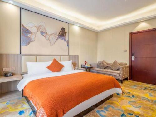 a bedroom with a large bed with an orange blanket at Oriental Hotel in Dongguan