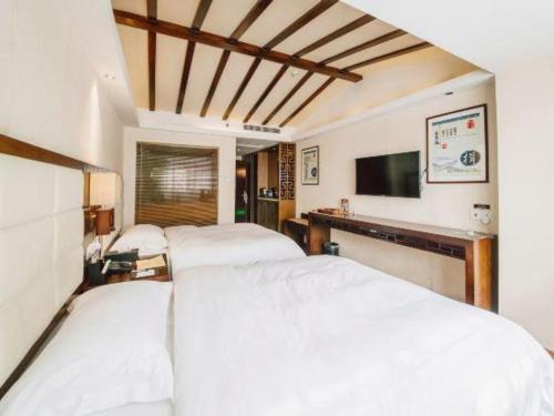 a bedroom with two white beds and a television at Oriental Hotel in Dongguan
