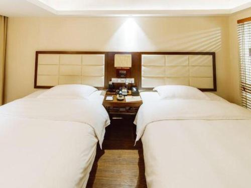 two beds in a hotel room with white sheets at Oriental Hotel in Dongguan