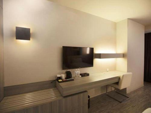 a hotel room with a desk with a tv on the wall at Jinjiang Metropolo Hotel - Qingdao Chengyang District Government in Qingdao