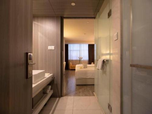 a bathroom with a sink and a bed in a room at Jinjiang Metropolo Hotel - Qingdao Chengyang District Government in Qingdao