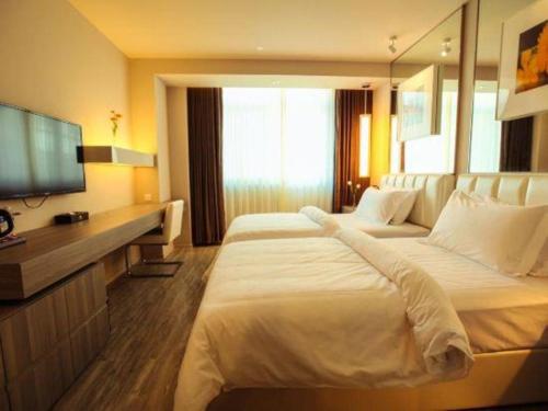 a hotel room with two beds and a flat screen tv at Jinjiang Metropolo Hotel - Qingdao Chengyang District Government in Qingdao