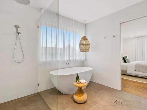 a bathroom with a bath tub and a bedroom at Opulence on Marine Parade in Kingscliff
