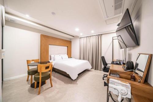 a hotel room with a bed and a desk and a television at Seven Motel Ansan in Ansan