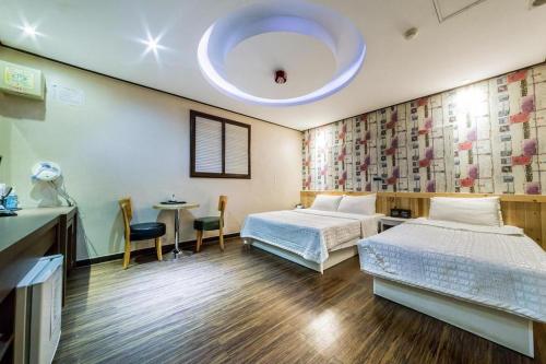 a bedroom with two beds and a table and a ceiling at Seven Motel Ansan in Ansan