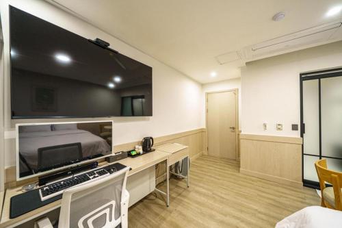 a room with a bed and a desk with a television at Seven Motel Ansan in Ansan