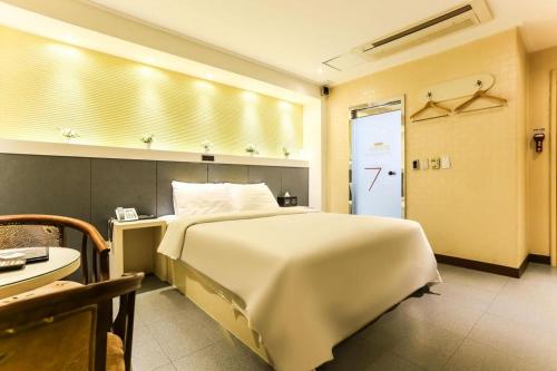 a bedroom with a large white bed and a table at Seven Motel Ansan in Ansan