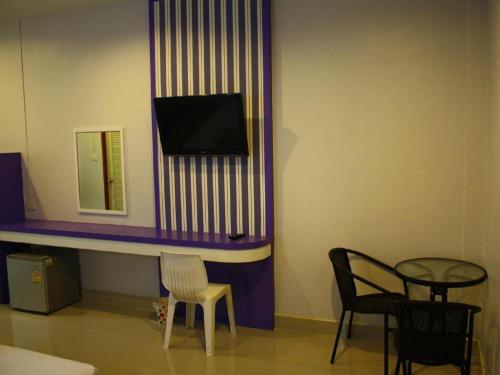 a room with two chairs and a tv on a wall at Sabai Ez Hotel in Songkhla