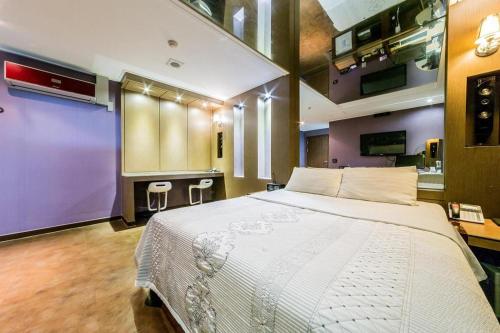 a bedroom with a large bed and a kitchen at Seven Motel Ansan in Ansan