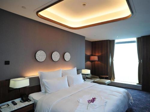 a bedroom with a large bed with white pillows at Chongqing The Lotus Hotel in Chongqing
