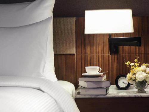 a bedroom with a bed and a table with a lamp and books at Chongqing The Lotus Hotel in Chongqing