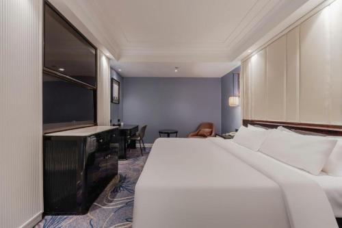 a hotel room with a bed and a flat screen tv at Jinjiang Metropolo Hotel Nanjing Confucius Temple Branch in Nanjing