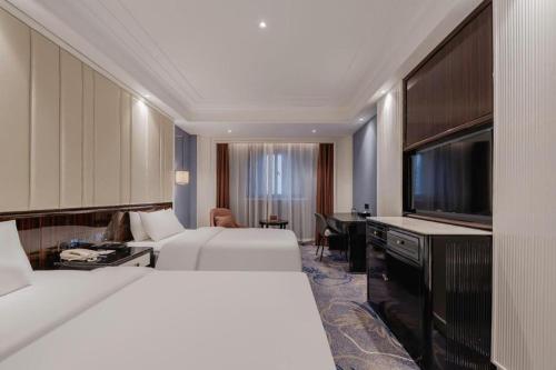 a hotel room with two beds and a flat screen tv at Jinjiang Metropolo Hotel Nanjing Confucius Temple Branch in Nanjing