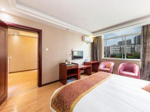 a hotel room with a bed and a desk and chairs at Super 8 Hotel Shiyan Beijing Middle Road in Shiyan