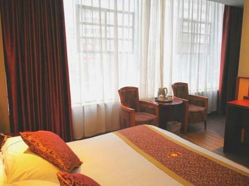 a hotel room with a bed and a table with chairs at Super 8 Hotel Shiyan Beijing Middle Road in Shiyan