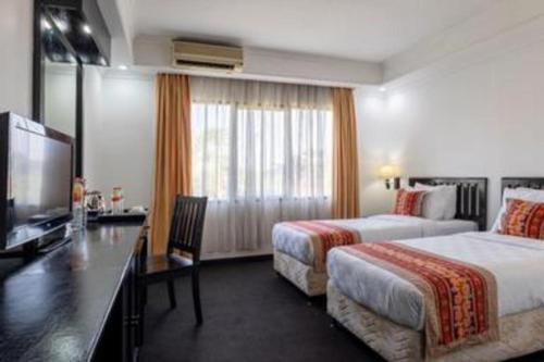 a hotel room with two beds and a flat screen tv at Jimbarwana Hotel in Negara
