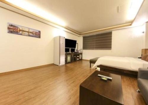 a room with a bed and a couch and a tv at H Hotel in Ulsan