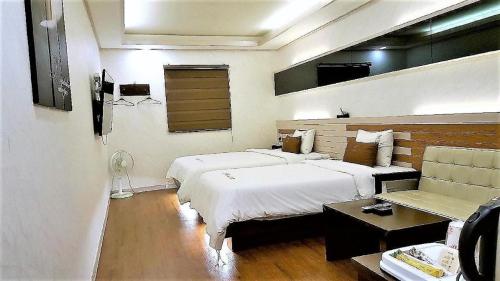 a hotel room with two beds and a couch at H Hotel in Ulsan
