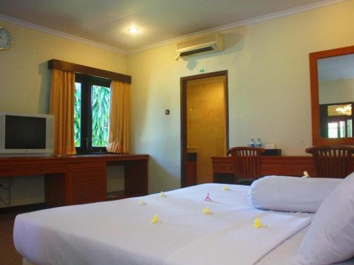 a bedroom with a white bed with flowers on it at Jimbarwana Hotel in Negara