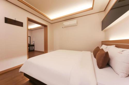 a bedroom with a large white bed with white pillows at H Hotel in Ulsan