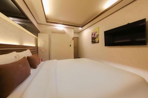 a bedroom with a white bed and a flat screen tv at H Hotel in Ulsan