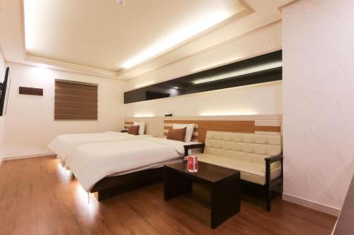 a bedroom with a large bed and a couch at H Hotel in Ulsan