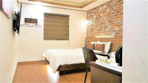 a bedroom with a bed and a desk with a television at H Hotel in Ulsan