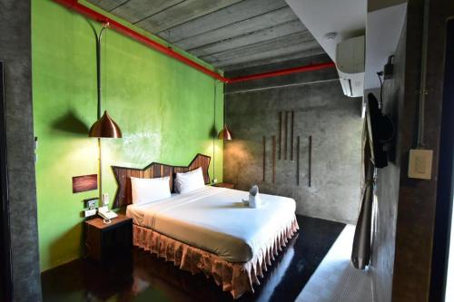 a bedroom with a bed and a green wall at Ps Extra Hotel in Hat Yai