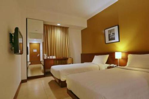 a hotel room with two beds and a bathroom at PARK HOTEL Cawang Jakarta in Jakarta