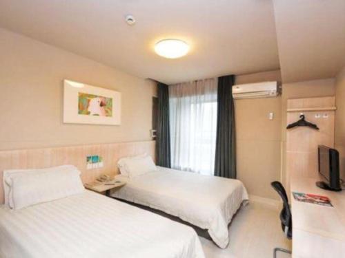 a hotel room with two beds and a television at Jinjiang Inn Wuhu Fangte Tech Museum Metro Station in Wuhu