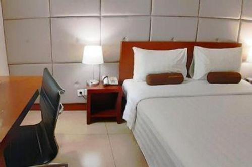 a hotel room with a bed and a desk with a phone at PARK HOTEL Cawang Jakarta in Jakarta
