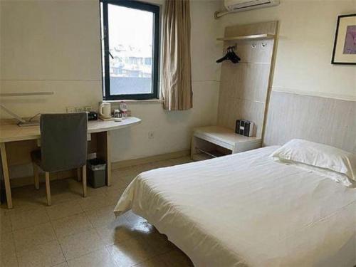a bedroom with a bed and a desk and a window at Jinjiang Inn Wuhu High-Speed Railway Station West Square in Wuhu