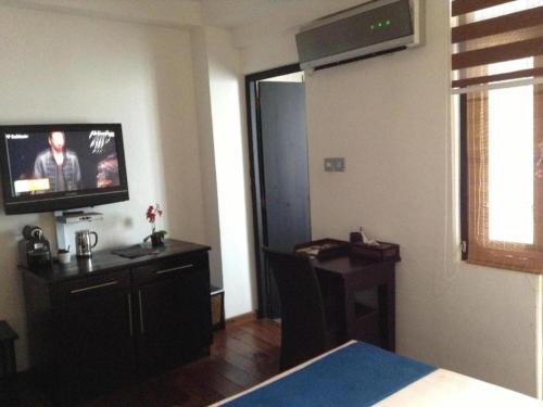 a room with a bedroom with a television and a desk at D Villas in Colombo
