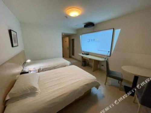 a room with two beds and a desk with a large screen at Jinjiang Inn Wuhu High-Speed Railway Station West Square in Wuhu