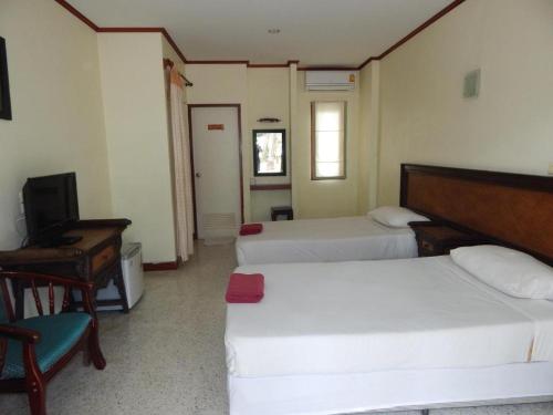 a bedroom with two beds and a desk and a television at Jinta Hotel Nathon Beach in Chaweng