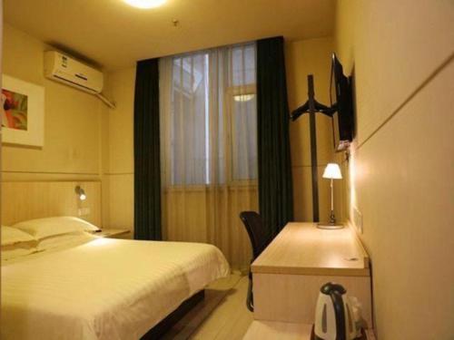 a bedroom with a bed and a desk and a window at Jinjiang Inn Pingyao Branch in Pingyao