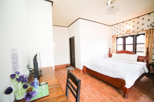 a bedroom with a bed and a tv in it at Maylay Guesthouse in Vang Vieng