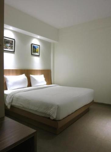 a bedroom with a large bed with white sheets and pillows at Hart Hotel Arjuna in Gili Trawangan
